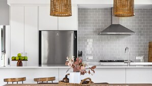 Una cocina moderna con armarios blancos, un refrigerador de acero inoxidable y un salpicadero de azulejos grises.