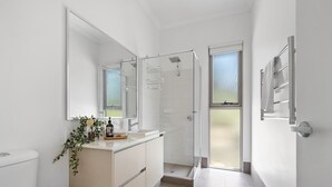 Un baño moderno con inodoro, lavamanos y zona de ducha.