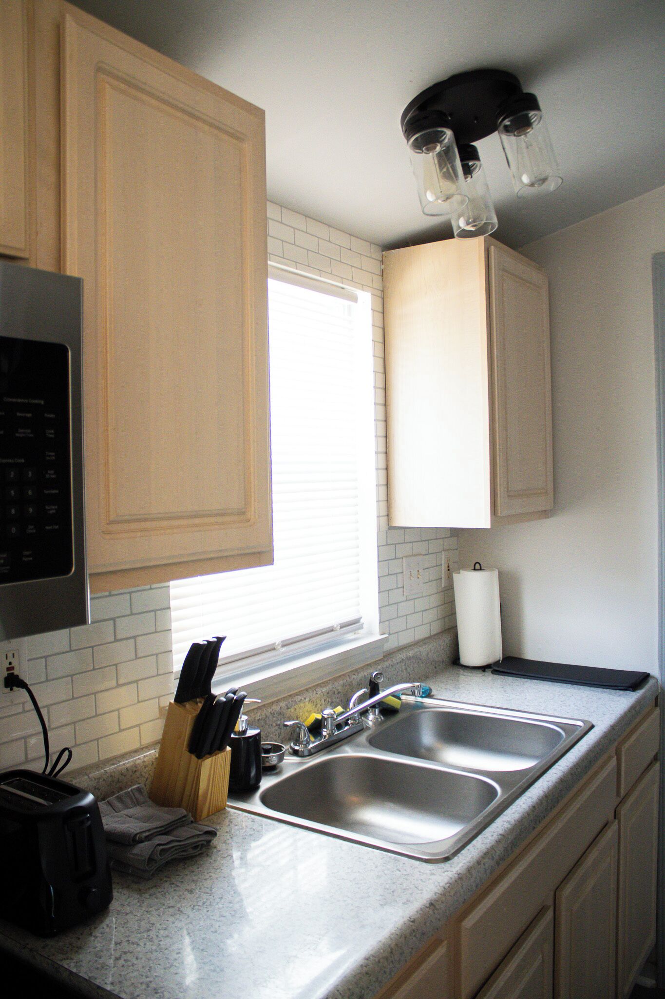 A kitchen with wooden cabinets, a double sink, a toaster, and a knife block.