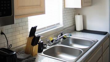 A kitchen with wooden cabinets, a double sink, a toaster, and a knife block.