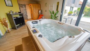 A modern bathroom with a large jacuzzi, wooden flooring, and a view of the outside.