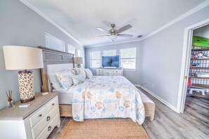A bedroom with a bed, bedside tables, a ceiling fan, a window, and a door leading to a closet.