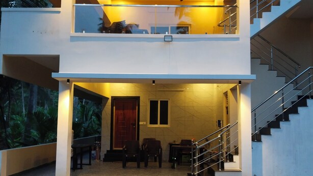 A two-story modern house with a balcony, a staircase, and a door leading to the interior. - LIMRA FARM HOUSE  (Anaimalai)