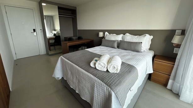 Ein Hotelzimmer mit einem großen Bett, einem Schreibtisch, einem Stuhl, einem Spiegel und einem Nachttisch.