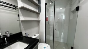 Et moderne badeværelse med en glasafskærmet brusekabine, et hvidt toilet og en sort bordplade med vask.