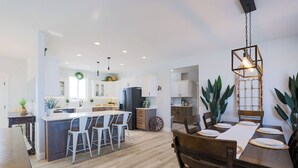 A modern kitchen with a central island, bar stools, and a dining area with a wooden table and chairs. - Cozy 6 bedroom home minutes from Rigby Lake (Rigby)
