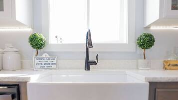 Una cocina con un lavabo blanco, armarios de madera y dos pequeñas macetas.