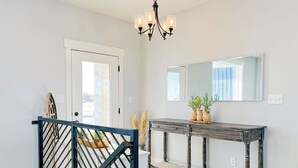 A hallway with a wooden console table, a mirror, and a staircase with a black railing. - Cozy 6 bedroom home minutes from Rigby Lake (Rigby)