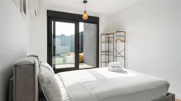 Un dormitorio moderno con una cama, un armario y vistas de la ciudad a través de un ventanal grande.