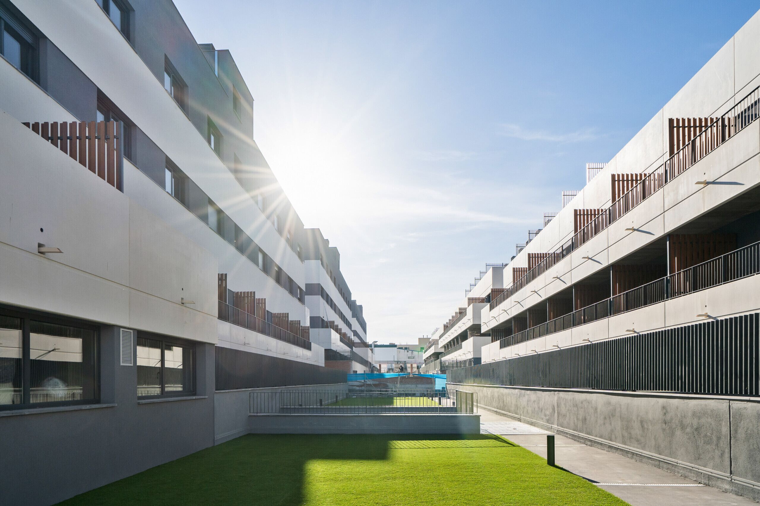 Un edificio moderno con un patio central, ventanas amplias y balcones.
