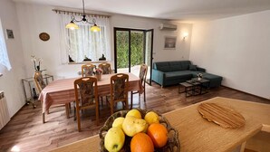 Un comedor con una mesa dispuesta para cuatro personas, un sofá y un frutero sobre la mesa.