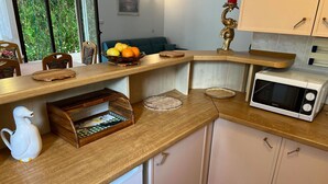 Una cocina con mostrador de madera, microondas y frutero.