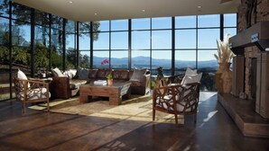 A spacious living room with a large window offering a mountain view, leather furniture, and a fireplace.