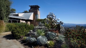 A modern house with a stone facade, a metal roof, and a view of the landscape.