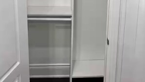 Un armario blanco con varios estantes y espacio para colgar.