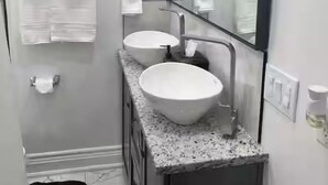 Un baño con dos lavamanos, un espejo grande y cuadros en la pared.
