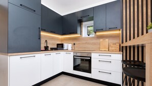 A modern kitchen with dark cabinets, white drawers, a built-in oven, and a wooden countertop.