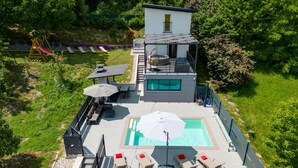 A modern house with a rooftop pool, outdoor seating, and a swing set.