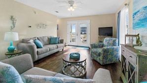 A living room with a sofa, armchairs, a coffee table, a TV, and a ceiling fan. - 3-Bedroom Gulf Views Retreat - 1 Min to Beach (Mexico Beach)