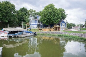 Une maison au bord du lac, dotée d’un quai, d’un espace abrité pour les bateaux et d’un escalier en bois menant à une terrasse.