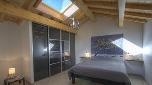 A bedroom with a large bed, a skylight, a sliding glass door, and a painting on the wall. - La Mine - SAINT MARTIN DU FRESNE (SAINT MARTIN DU FRESNE)