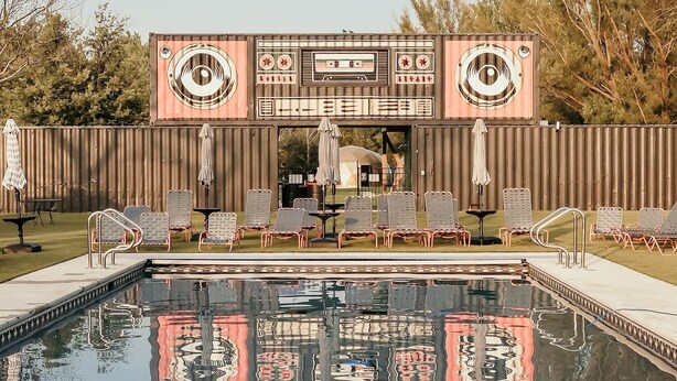 A pool area with lounge chairs and a large decorative screen. - Customizable Multi-Dome Buyout (South Haven)