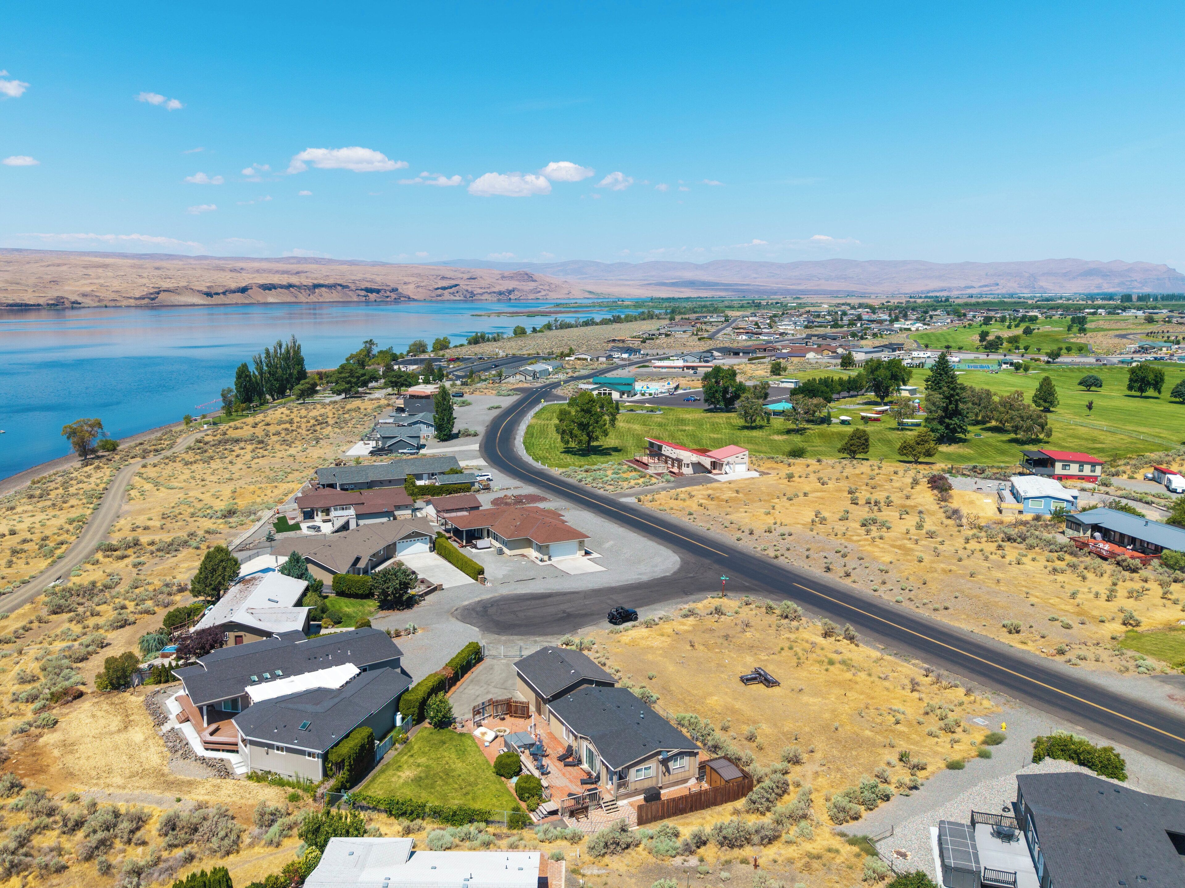 A residential area with houses, a curved road, and a lake in the background.