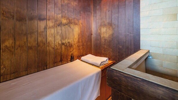 A wooden room with a bench, a small table with a towel, and a stone wall. - Myhotel Okazaki (Okazaki)