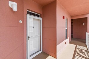 A corridor with a closed door, a fire extinguisher, and a number sign. - Atlantis 205C (St. Augustine Beach)