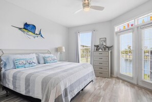 A bedroom with a bed, a dresser, a ceiling fan, and a window with blinds. - Atlantis 205C (St. Augustine Beach)