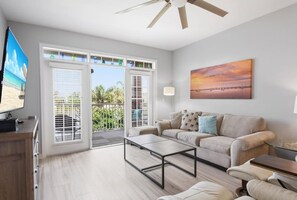 A modern living room with a sofa, coffee table, and TV. - Atlantis 205C (St. Augustine Beach)