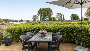 A wooden deck with a table and chairs, a potted plant, and a large umbrella. - Awesome home in Sydals with WiFi (Sydals)
