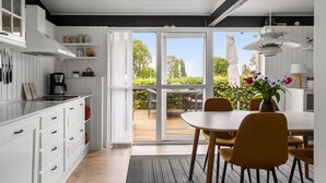 A modern kitchen with white cabinetry, a coffee machine, and a dining area with yellow chairs and a table. - Awesome home in Sydals with WiFi (Sydals)