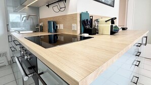 A modern kitchen with a wooden countertop, stainless steel appliances, and a large window.