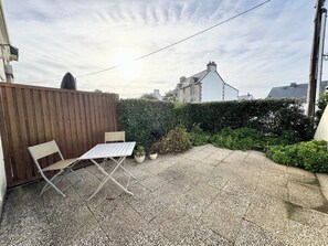 A patio with a table and chairs, surrounded by a wooden fence and a hedge. - Lovely ! T2 Top Cosy - Terrasse (Quiberon)