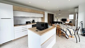 Une cuisine moderne avec des meubles blancs, un plan de travail en bois et un four à micro-ondes encastré.