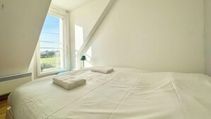 A bedroom with a large bed, a skylight, and a view of the outdoors.