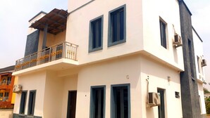 A two-story building with a balcony, air conditioning units, and a small entrance door. - Bly & Schol Apartments (Abuja)