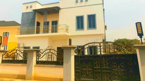 A two-story building with a balcony, a gated entrance, and a decorative iron gate. - Bly & Schol Apartments (Abuja)