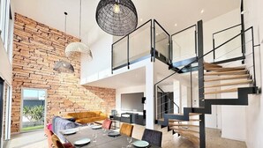 Um interior moderno com área de jantar, escada e sala de estar com parede de pedra.