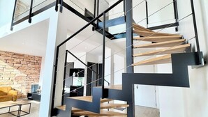 Um interior moderno com uma escada em vários níveis, com corrimãos de metal preto e degraus de madeira.