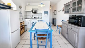 Cocina compacta con comedor, armarios blancos, microondas y horno tostador.