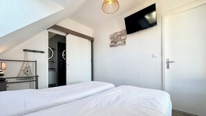 Un dormitorio con una cama grande, un televisor montado en la pared y una lámpara en el techo.
