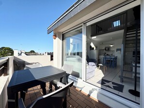 Een balkon met een tafel en stoelen, een schuifdeur naar een keukenruimte met een eettafel en stoelen.