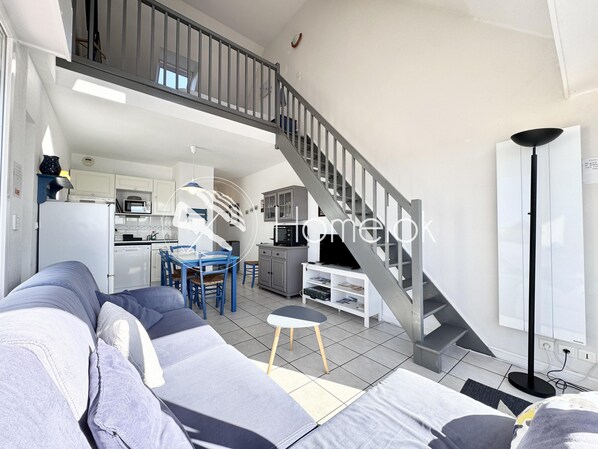 Een moderne woonkamer met een grijze trap, een eethoek en een keuken.