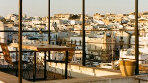 Una terraza con mesa y sillas, con vistas a una zona urbana densamente poblada de edificios.