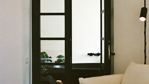 Una habitación con sofá, una puerta que da al exterior y una mesita con una planta.