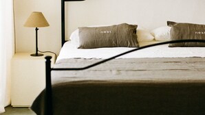 Una cama con estructura metálica negra, una lámpara color beige y dos almohadas con la palabra 'nest'.