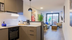 Een moderne keuken met inbouwapparatuur, een eetgedeelte met uitzicht en een woonruimte met een plant en kunstwerken.