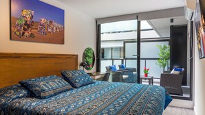 Een slaapkamer met een groot bed, uitzicht naar buiten en een schilderij aan de wand.